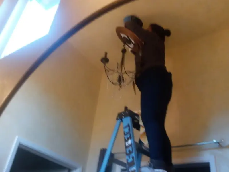 Electrician installing a chandelier in a Moscow Mills residence